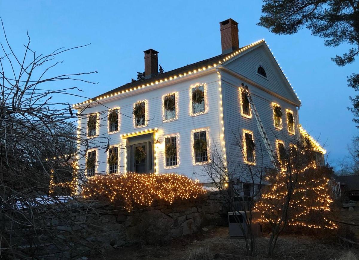 Colonial home with warm white lights on every window and roofline